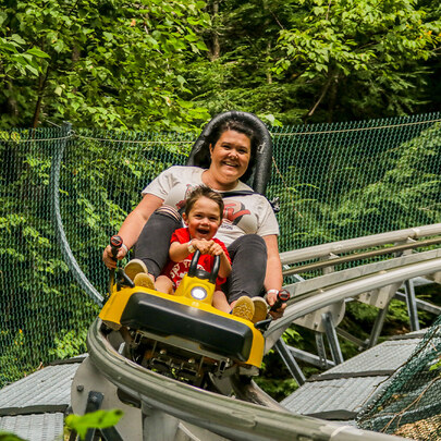 Mom and child smiling on mountain coaster