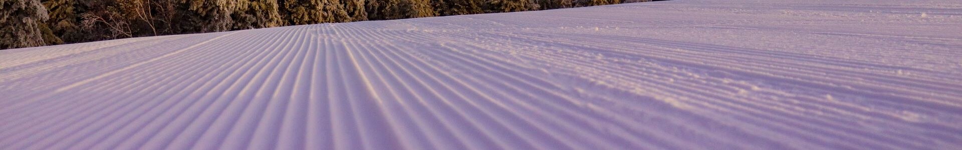 Close-up of corduroy-groomed snow at the summit