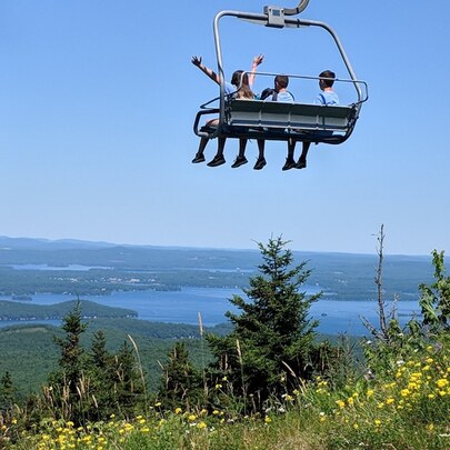 Group of people riding a lift down mountain overlooking mountains and lake