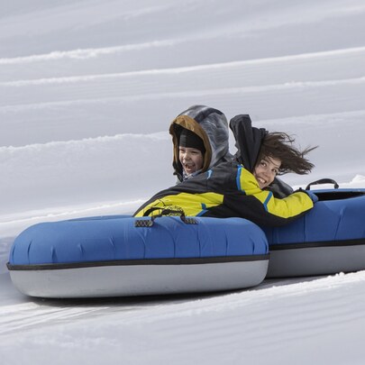 Two  smiling children in snowtubes on the mountain