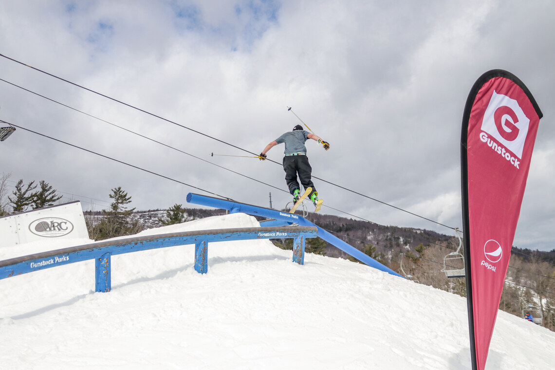 Skier jumps to a second blue rail feature.