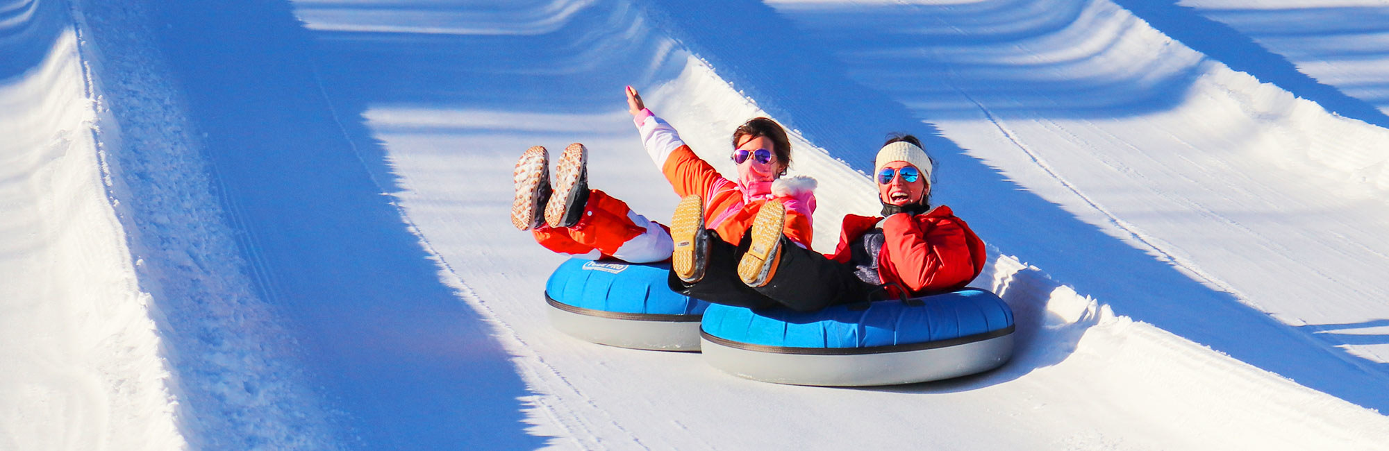 Two girls tubing down the hill.
