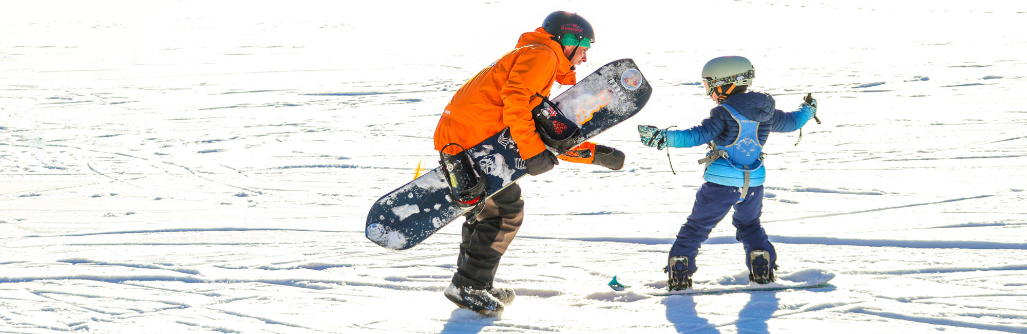 Snowboard instructor with child on snow