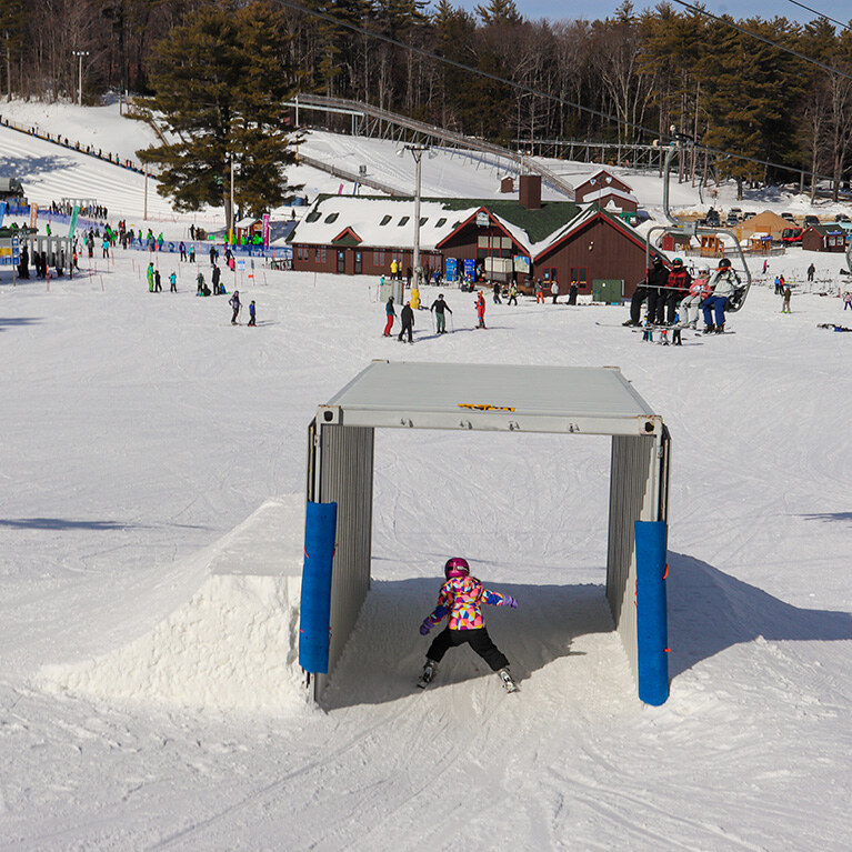 Child in pink jacket going through Adventure Slope box