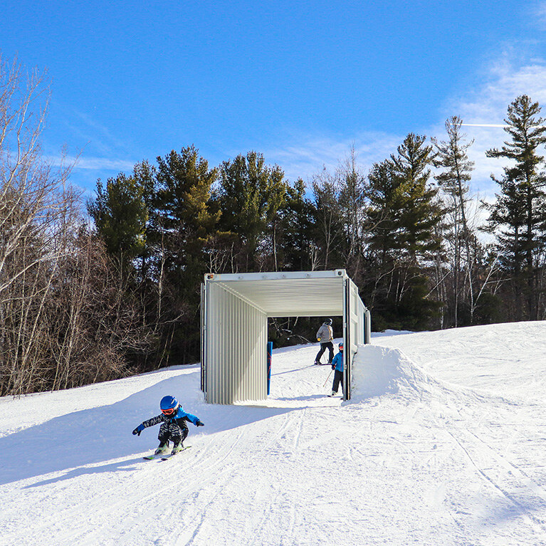 Child in blue jacket in front of Adventure Slope box